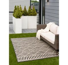 a white couch sitting on top of a grass covered field next to a planter