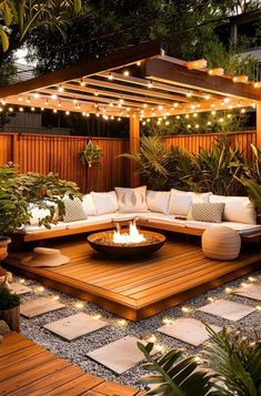 an outdoor living area with wooden flooring and lights on the roof, surrounded by plants