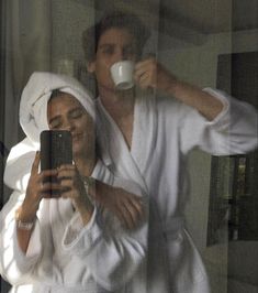 a man and woman in bathrobes taking a selfie with their cell phone