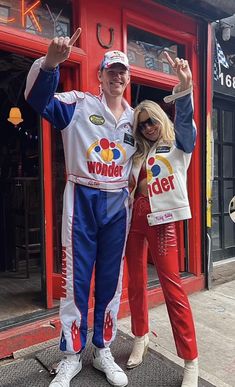 a man and woman posing for a photo in front of a store with their hands up