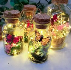 three glass jars filled with lights and butterflies