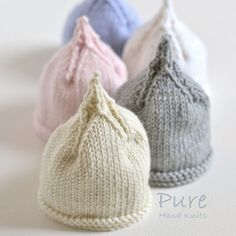 three knitted beanies sitting next to each other on top of a white surface