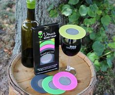 a bottle of wine and some coasters on a tree stump next to a glass of wine