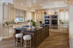 a large kitchen with an island in the middle and two stools at the end