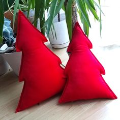 two red pillows sitting on top of a wooden table next to a potted plant