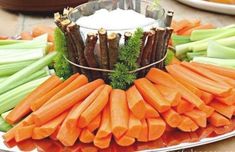 carrots and celery arranged on a platter with dip in the middle