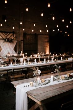 tables with candles and flowers are set up for a wedding reception in an old barn