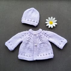 a knitted baby sweater and hat with a flower