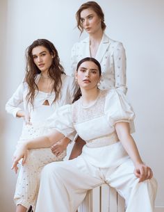 three women in white outfits sitting on a radiator and posing for the camera