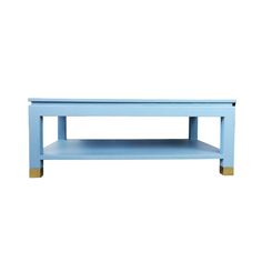 a blue coffee table with gold legs and a shelf on the bottom, against a white background