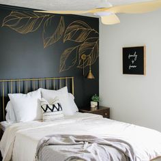 a black and white bedroom with gold leaf stencils on the wall above the bed