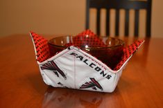 an origami boat sitting on top of a wooden table next to a bowl