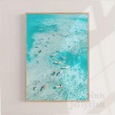 an aerial view of people swimming in the ocean with blue water and white sand below