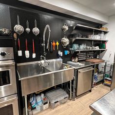 an industrial kitchen with stainless steel appliances and shelves filled with utensils on the wall