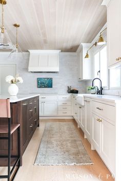 a large kitchen with white cabinets and wooden floors, along with an area rug on the floor