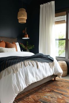 a bedroom with dark walls and white bedding, rugs on the floor and windows