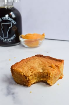 a piece of cake sitting on top of a counter next to a bottle of syrup