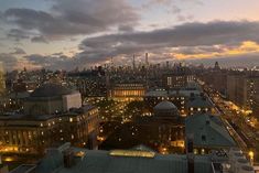 the city skyline is lit up at night with clouds in the sky and lights on buildings