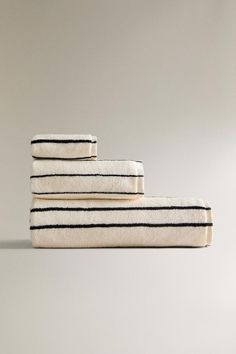 three towels stacked on top of each other in white and black striped linens, with one folded up to the side