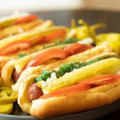 three hot dogs with mustard, ketchup and relish sitting on a plate