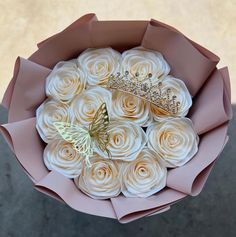 a bouquet of white roses with a tiara on the top and a butterfly in the middle