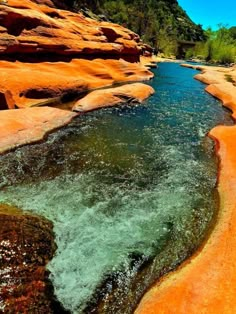 the river is flowing through some red rocks