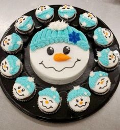 there is a cake with frosting and cupcakes in the shape of a snowman