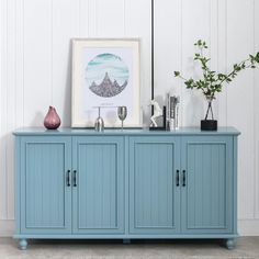 a blue sideboard with two vases on top and a framed photograph above it