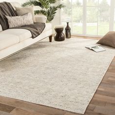 a living room with a couch, chair and rug on the hardwood floor next to a window