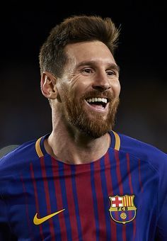 a man with a beard smiles at the camera while wearing a blue and red shirt