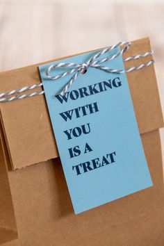 a brown bag with a blue tag attached to it that says working with you is a treat