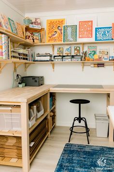 an organized craft room with wooden shelves and art on the wall, including a desk