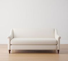 a white couch sitting on top of a hard wood floor next to a white wall