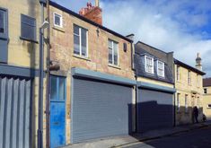 an empty street with two garages and one person walking on the sidewalk in front of it