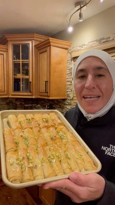 a woman in a hijab is holding a tray of food that includes rolls