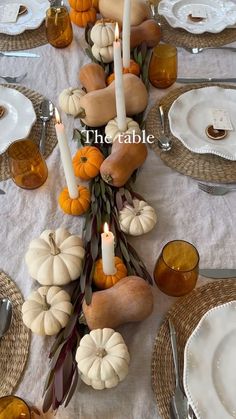 the table is set with candles, pumpkins and gourds