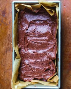 a pan filled with chocolate frosting on top of a wooden table