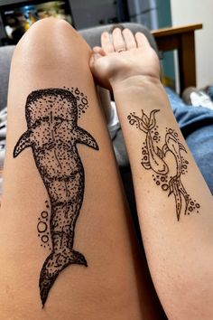 two people with tattoos on their arms, one has a shark and the other has a lizard