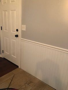 an empty room with a white door and hard wood flooring on the ground next to it