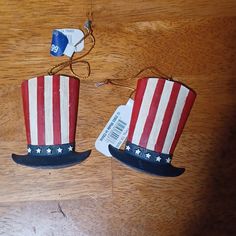 two red, white and blue top hats with tags attached to them on a wooden table