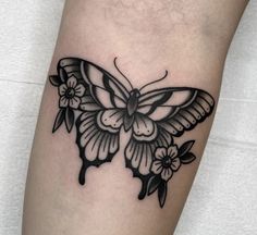 a black and white butterfly tattoo on the left leg, with flowers around its wings