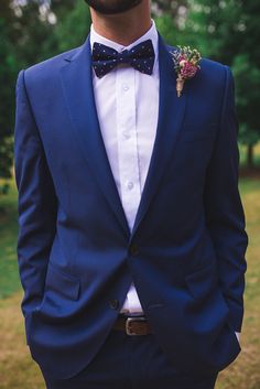 a man wearing a blue suit and bow tie with a flower in his lapel