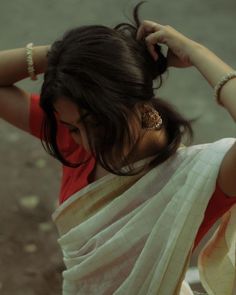 a woman in a white sari is holding her hair