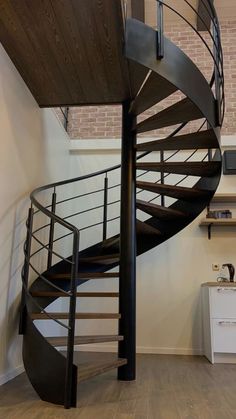 there is a spiral staircase in the middle of this room with wood floors and white walls