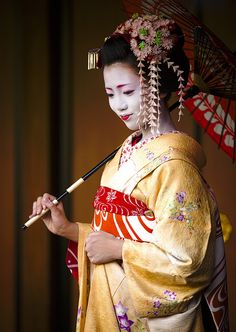 a woman dressed in geisha clothing holding an umbrella