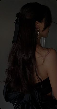 a woman with long dark hair wearing a black dress and large bow in her hair