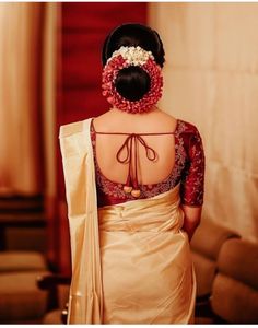 the back of a woman's dress with flowers in her hair and an elaborate headpiece