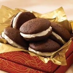 chocolate cookies with white frosting in a red box on top of gold wrapping paper