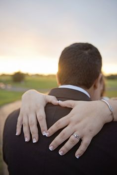 a bride and groom embracing each other in front of the sun setting on their wedding day