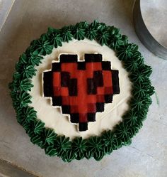 a cake decorated with green leaves and an image of a heart in the shape of a pixel